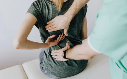 Fisioterapeuta avaliando a postura da coluna lombar de um paciente