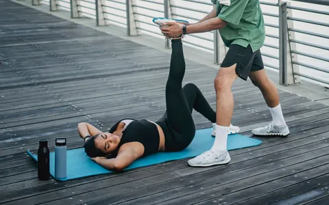 Pessoa alongando a perna sentada sobre um tapete de exercícios