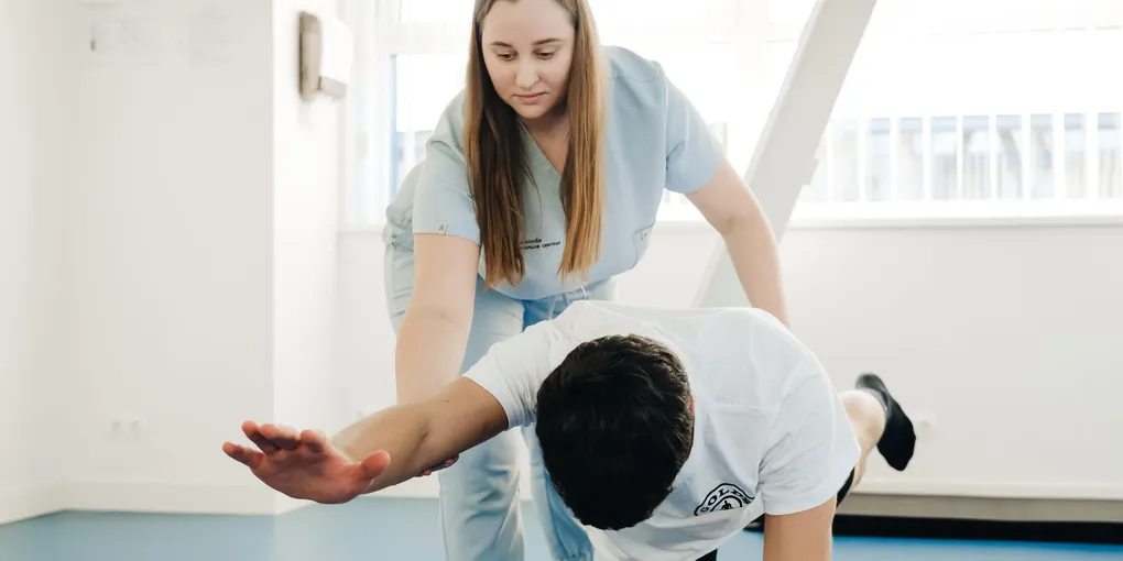 Fisioterapeuta orientando paciente durante exercício de mobilidade em quadrupedia