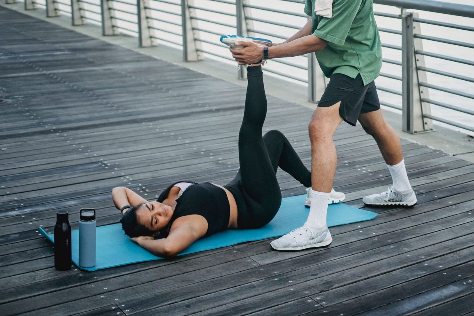 Pessoa alongando a perna sentada sobre um tapete de exercícios