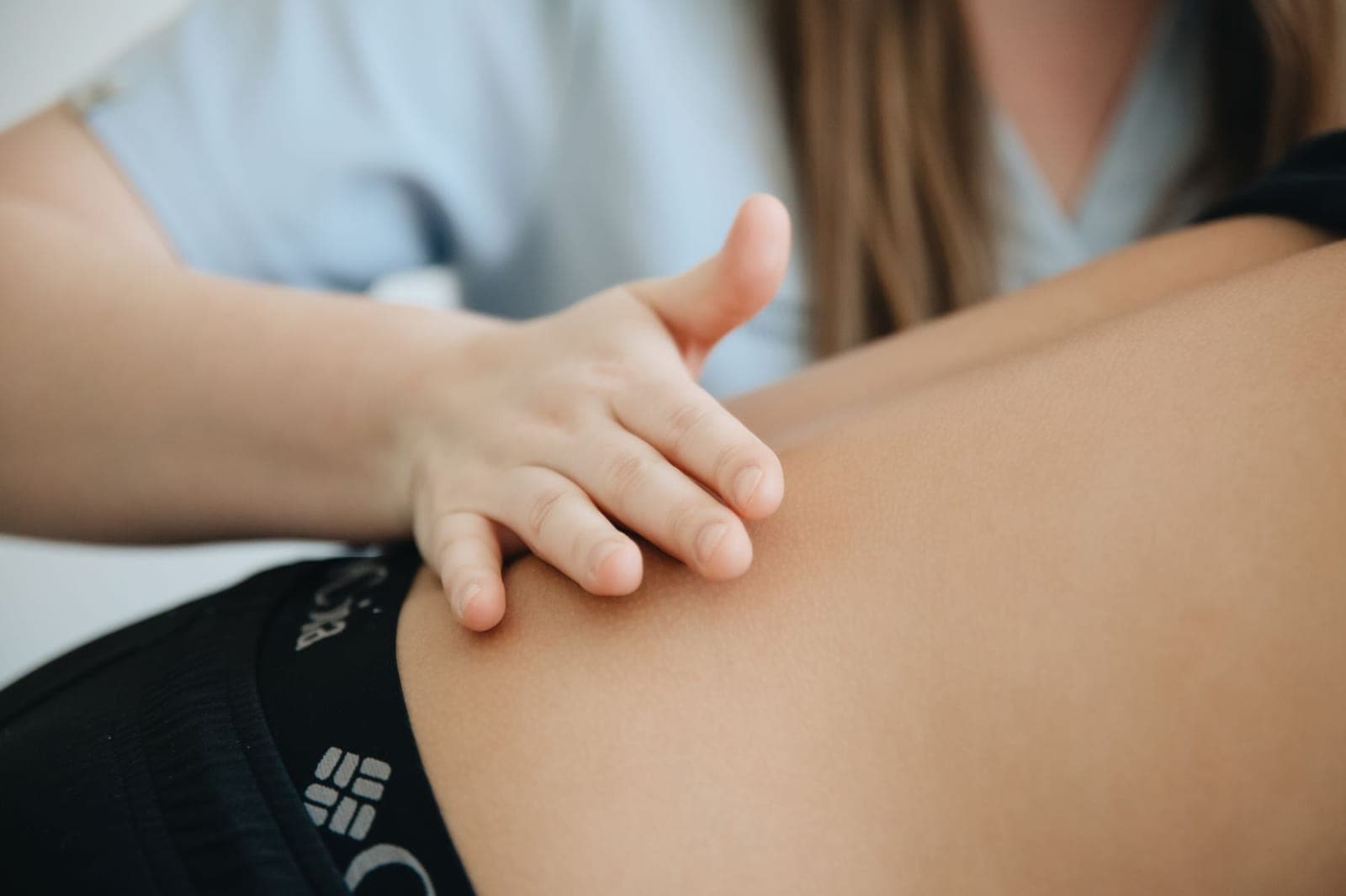 Fisioterapeuta examinando a região lombar baixa e o quadril de um paciente durante avaliação