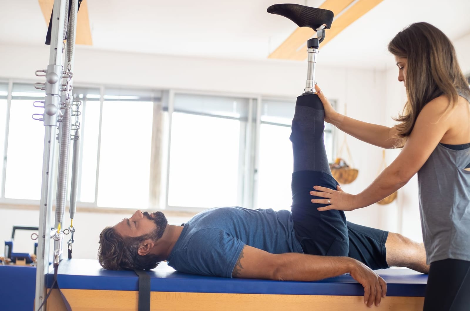 Fisioterapeuta apoiando a prótese de um paciente durante exercício de fortalecimento do quadril